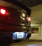 Rear view of Mitsubishi Evo X with bright red tail lights and white LED license plate lighting in a garage.