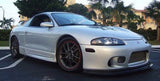 Silver Mitsubishi Eclipse 2G parked in a tropical setting, showcasing custom wheels and lowered stance.